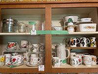 Shelves with multiple floral china mugs, a white ceramic teapot, and other kitchenware shown for reference.