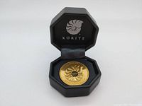 Medallion displayed inside original black octagonal storage case with Korite logo on lid interior.