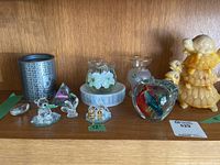 Shelf setup showing a collection of Swarovski crystal figurines including bear, rabbit, a small gold accent animal group, glass pyramid, floral glass vase, frosted vase, glass apple paperweight with birds, and yellow ceramic turtle statue.