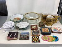 Full lot showing mugs, salad bowl, pasta plates, escargot dishes, and coasters arranged on a white surface.