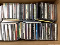 Photo of boxed collection of about 50 used music CDs in jewel cases, spines visible.