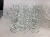 Front view of 10 white wine glasses with detailed cut crystal pattern and faceted stems. Glasses are clear. Chips and wear not visible in this angle.