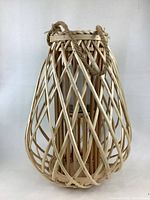 Front and partial side view of a large natural wicker candle holder with rope handles, showing construction and some cracks in wicker.
