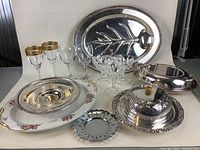 Full view of all the lot items showing platters, dome dish, pedestal tray, crystal glasses.