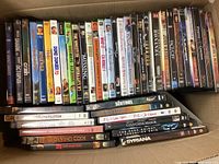 Top view of a box filled with DVD cases showing various titles and a mix of genres including drama, romance, and thriller.