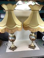Pair of tall European style table lamps with fabric shades on brass feet, painted porcelain body with classical scenes