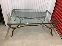 Front view of the rectangular glass coffee table showing the metal base with curved legs and cross supports.