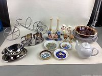 Full lot view showing Crof Van Henneberg soup plates, bicycle wine caddy, ceramic teapot, decorative plates, candlesticks, salt and pepper shakers, silver-tone creamers and gravy boat