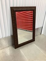 Full front view of the rectangular mirror showing the decorative metal frame and clear reflective glass surface.