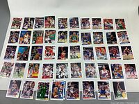 Wide layout of approximately 51 NBA basketball trading cards spread evenly on white background, showing various players and designs.