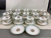 Full set of 14 Royal Doulton fine bone china teacups and saucers arranged in rows showing fronts and tops of items.