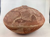 Top side view of a large rounded pottery vessel with earthy brown and terracotta hues, showing the textured surface and small top opening.