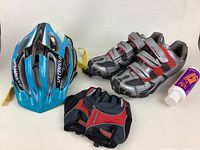 Lot showing blue Specialized helmet, gray and red cycling shoes size 46, cycling gloves, and a tube of cream
