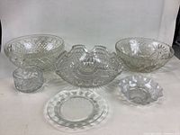 Overview of six vintage cut glass bowls and dishes of various shapes and sizes, showing intricate vintage designs and clear glass with no visible chips.