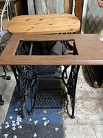 View from above showing wooden top with rectangular opening and cast iron base of treadle sewing machine.