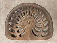 Top view of cast iron tractor seat showing perforated pattern and Toronto logo