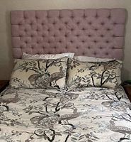 Front view of pink tufted upholstered headboard mounted behind bed with pillows in front, showing full size and tuft pattern.