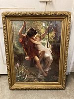 Full view of the framed print showing couple on swing and ornate gold frame with wear visible.
