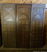 Front view of the three heavy wood panels arranged side by side, showing the geometric raised squares and grid design.