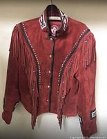 Full front view of red suede jacket displaying fringe, beadwork, and snap closure.