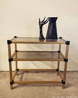 Full view of the vintage shelf showing gold metal frame and two smoked glass shelves in place with bottom missing.