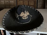 Full view of the black vintage sombrero showing the embroidered eagle and sword design on the crown with stitched brim.
