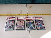 Four unopened Donruss collector baseball card packs, displayed on a table with measuring tape to show scale