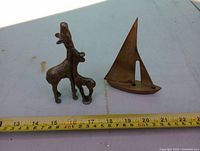 Photo of two brass giraffes and brass sailboat next to measuring tape showing scale.