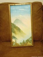 Front photo showing full framed oil painting of mountain landscape on a chair.