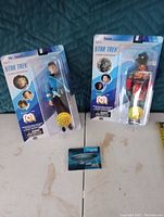Photo of the two Star Trek figures in blister packs (Mr. Spock and Gorn) with collector card on a blue quilt background.