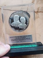 Front view of John and Sarah Churchill silver proof coin encapsulated in clear display case with black base and descriptive plaque.