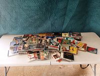 Large grouping of music CDs laid out on two folding tables showing different album covers and jewel cases.