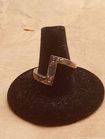 Photo of sterling silver ring displayed on a black ring holder, showing the geometric design and embedded stones