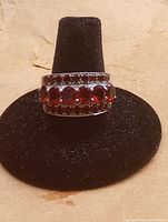 Front view of sterling silver ring with two rows of red gemstones on black stand.