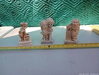 Three Russ Berries figurines side by side with measuring tape in front showing sizes.