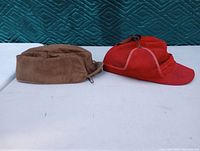 Side view of the brown and red vintage hunting hats lying flat showing shape and materials.