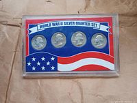Front view of sealed plastic display case with four World War II silver quarters in a red, white, and blue card labeled 'WORLD WAR II SILVER QUARTER SET'