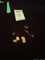 Overview on black cloth of all pieces: two oval cufflinks, signet ring, tie tack with chain, two stud earrings