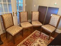 Four chairs arranged in a row against French doors with wooden panels behind