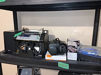 Overview of all items on shelf including bill counter, Lenovo tablet, speaker, cables, and small boxed items.