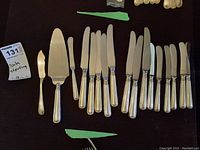 All 17 pieces arranged: 8 dinner knives, 7 butter knives, 1 cake server, 1 narrow butter cutter