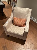 View of the large plush armchair from a slightly angled front showing fabric pattern and accompanying throw pillow.