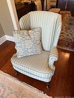 Front view of upholstered wingback armchair with throw pillow