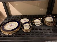 Set of Aynsley china including plates, teacups and saucers with blue and gold trim and floral design