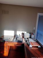 Wide view of desk with office supplies including papers, binders, and paper cutter.