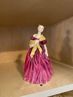 Front view of the Royal Doulton figurine in a dark pink dress with yellow shawl.
