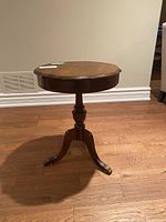 Photo of the wood round pedestal end table from the side to show full height and claw feet.