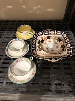 Photo showing three teacups each with a matching saucer and two larger plates including Royal Crown Derby platter