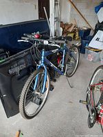Full side view of blue S1800 mountain bike with flat tires, showing frame, handlebars, tires, and adjacent items.