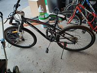 Side view of black and red Xranked mountain bike on kickstand showing frame, tires, and handlebar.